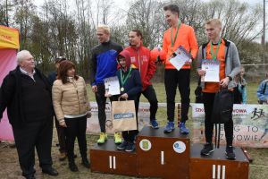 Zdjęcie: młodzież na podium i osoby wręczające nagrody podczas biegów przełajowych