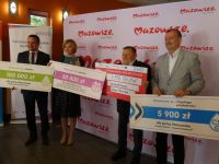 Zdjęcie: trzech mężczyzn i kobieta trzymający plansze z informacją o uzyskanym dofinansowaniu