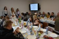 Zdjęcie: osoby siedzące przy uroczystym spotkaniu wielkanocnym w Klubie Seniora