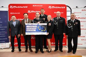 Zdjęcie: Marszałek, Burmistrz Mszczonowa wraz ze strażakami trzymający czek na dofinansowanie zakupu wozu bojowego