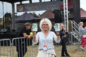 Zdjęcie: Kobieta trzymająca puszki na zbiórkę, w tle scena