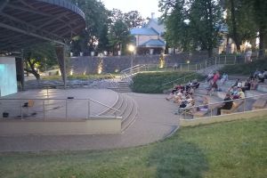 Zdjęcie: osoby oglądające kino pod chmurką w amfiteatrze