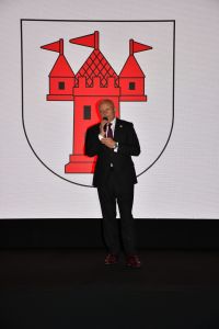 Zdjęcie: mężczyzna na scenie w tle herb Mszczonowa