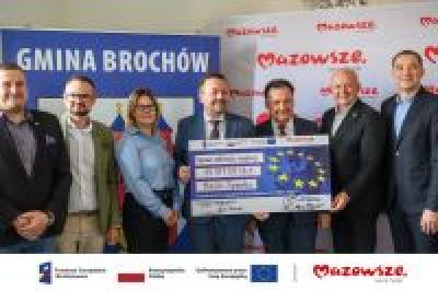 Zdjęcie: osoby trzymające czek informujący o dofinansowaniu