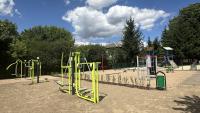 Zdjęcie: siłownia plenerowa, w tle plac zabaw