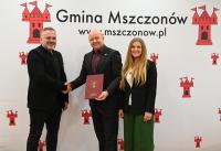 Zdjęcie: dwóch mężczyzn i kobieta stojący na ściance promocyjnej gminy Mszczonów